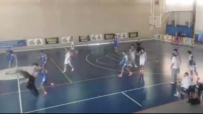 Un árbitro de baloncesto cae al suelo tras ser golpeado por la espalda por un jugador